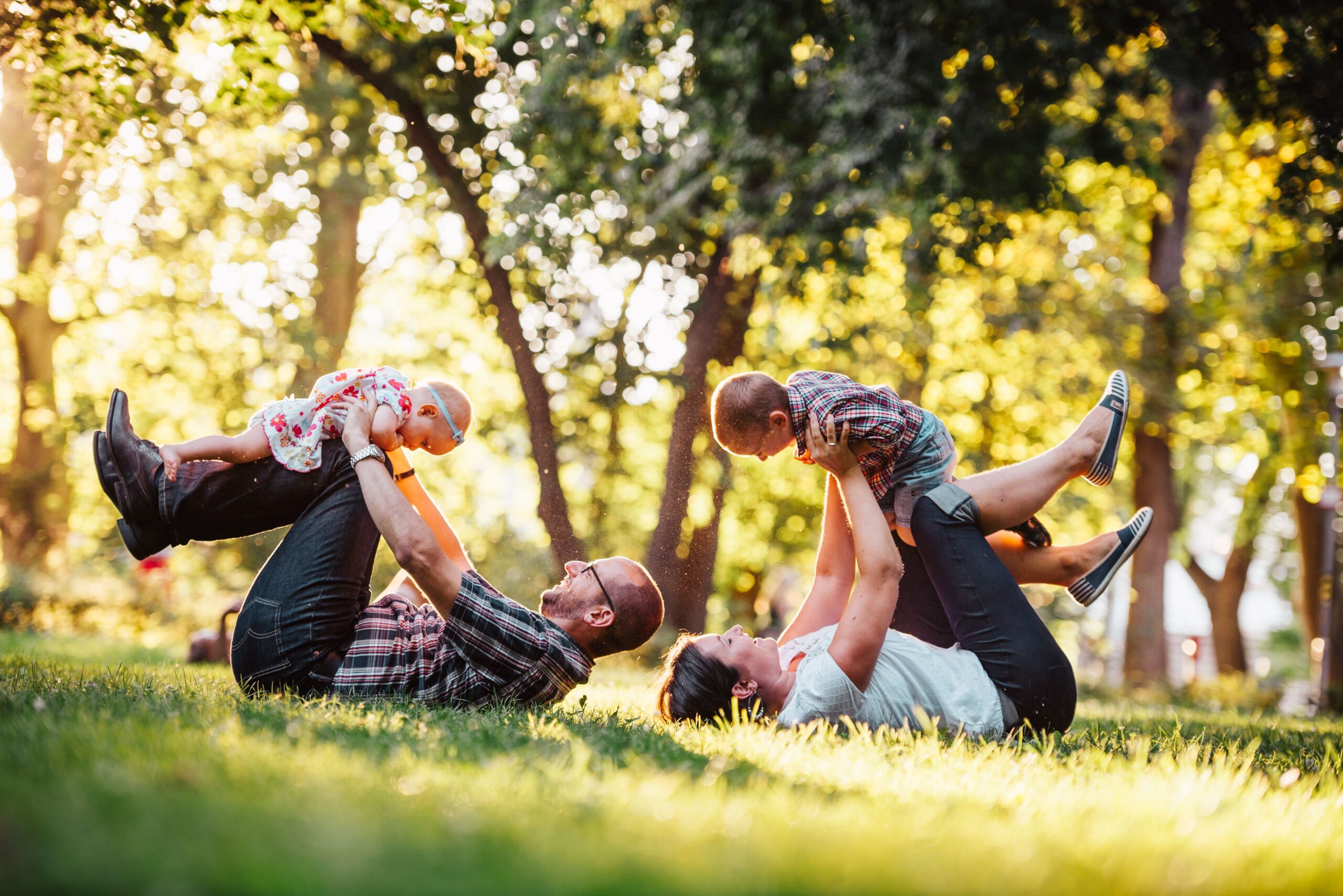 A mother and father playing with their children in a park